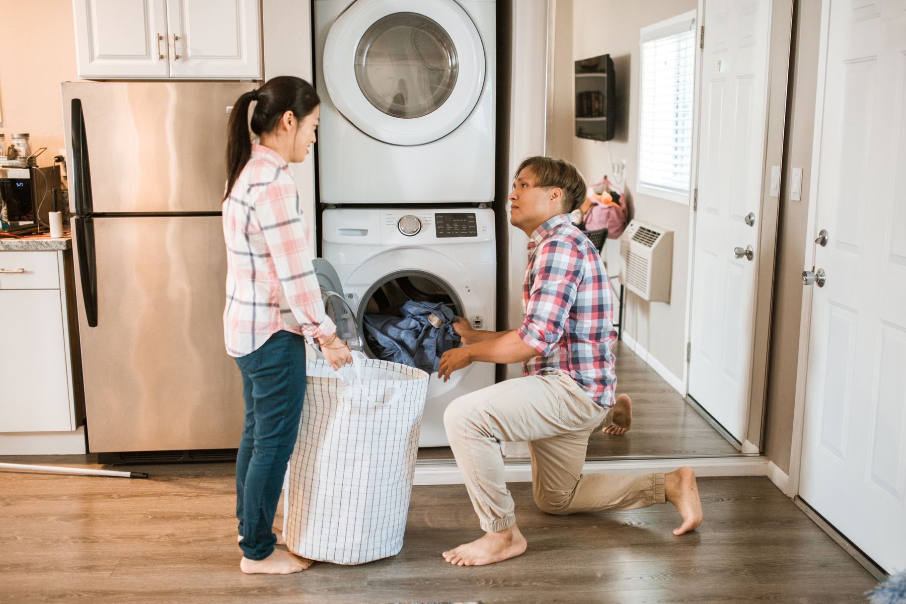 Couple sharing laundry responsibilities beside a washing machine