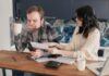 Couple talking about money while reviewing financial documents at a kitchen table