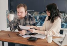 How to Talk About Money With Your Partner Without Fighting Couple talking about money while reviewing financial documents at a kitchen table