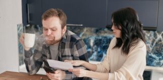 Couple talking about money while reviewing financial documents at a kitchen table