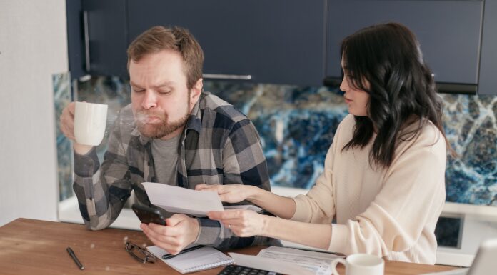 Couple talking about money while reviewing financial documents at a kitchen table