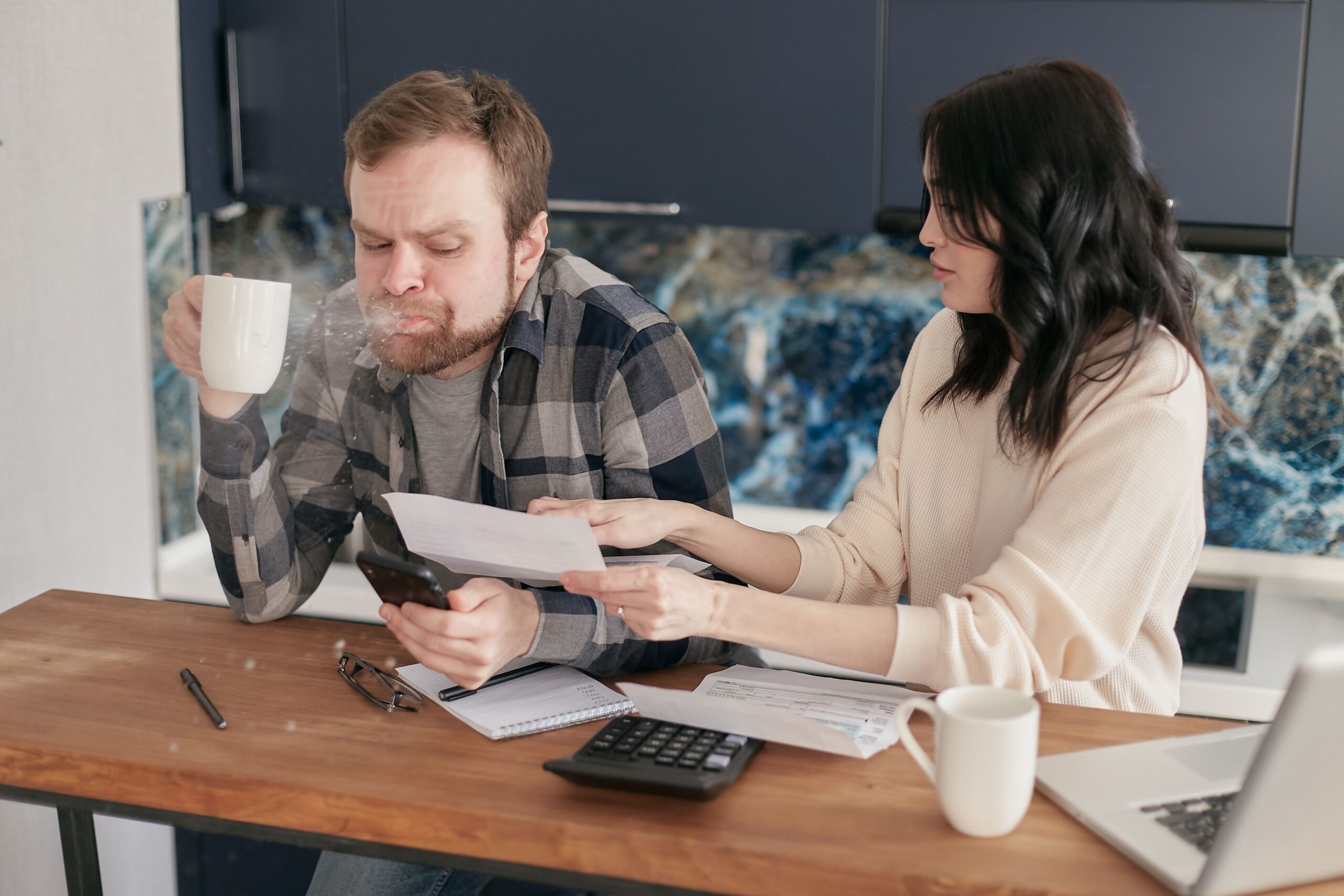 Couple talking about money while reviewing financial documents at a kitchen table
