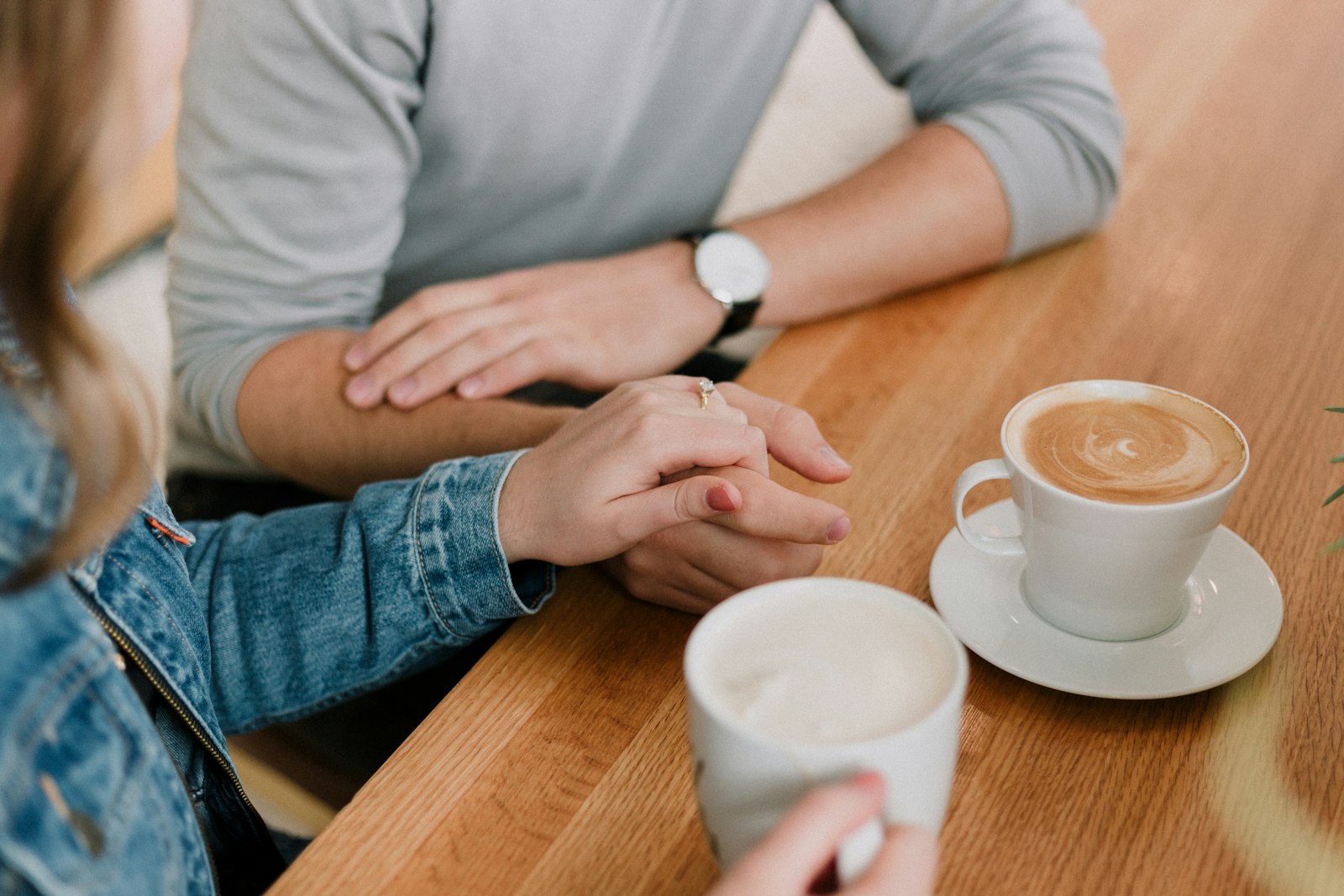 Couple holding hands across a table, representing mutual comfort and growing attraction on a date