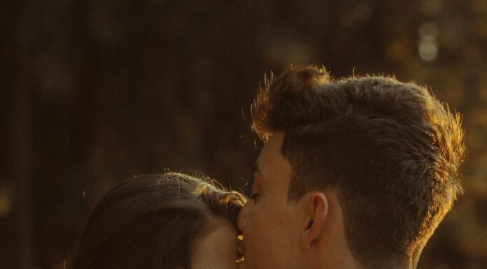Partner showing quiet affection through a kiss on the forehead