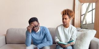Couple sitting on a couch having a tense conversation while working through relationship anxiety