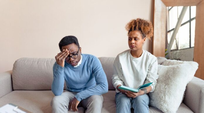 Couple sitting on a couch having a tense conversation while working through relationship anxiety