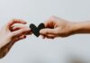 Two people holding a paper heart while starting a new relationship