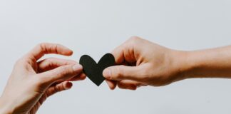 Two people holding a paper heart while starting a new relationship