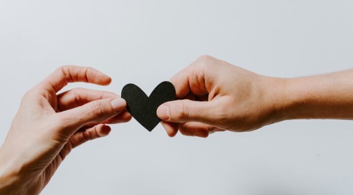 Two people holding a paper heart while starting a new relationship