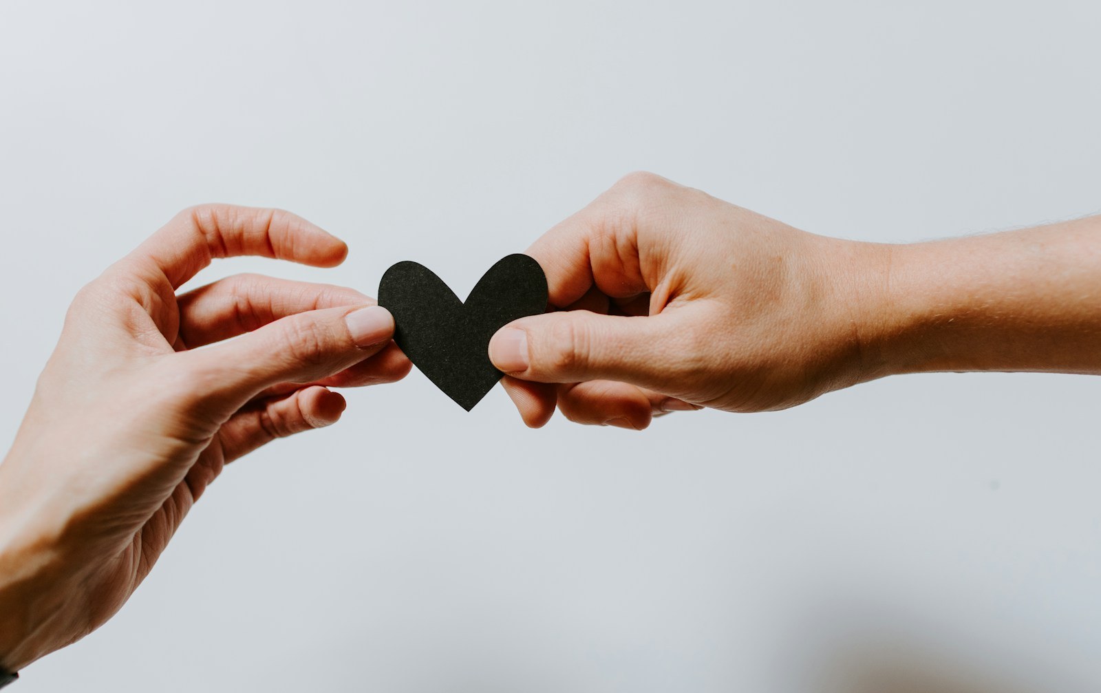 Two people holding a paper heart while starting a new relationship