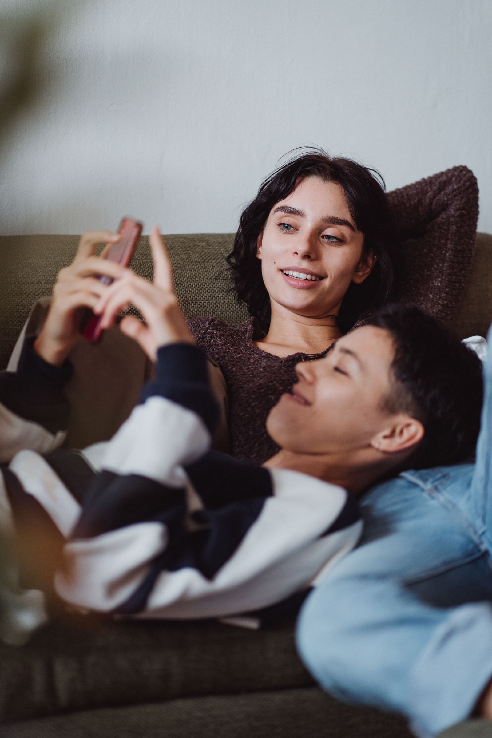 Couple relaxing closely on a sofa while looking at a phone together