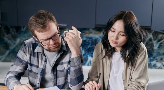 Couple discussing joint and separate bank accounts at home