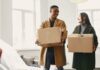 Couple carrying moving boxes while considering a relocation together