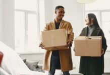 Couple carrying moving boxes while considering a relocation together
