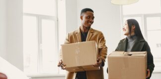 Couple carrying moving boxes while considering a relocation together
