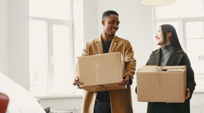 Couple carrying moving boxes while considering a relocation together