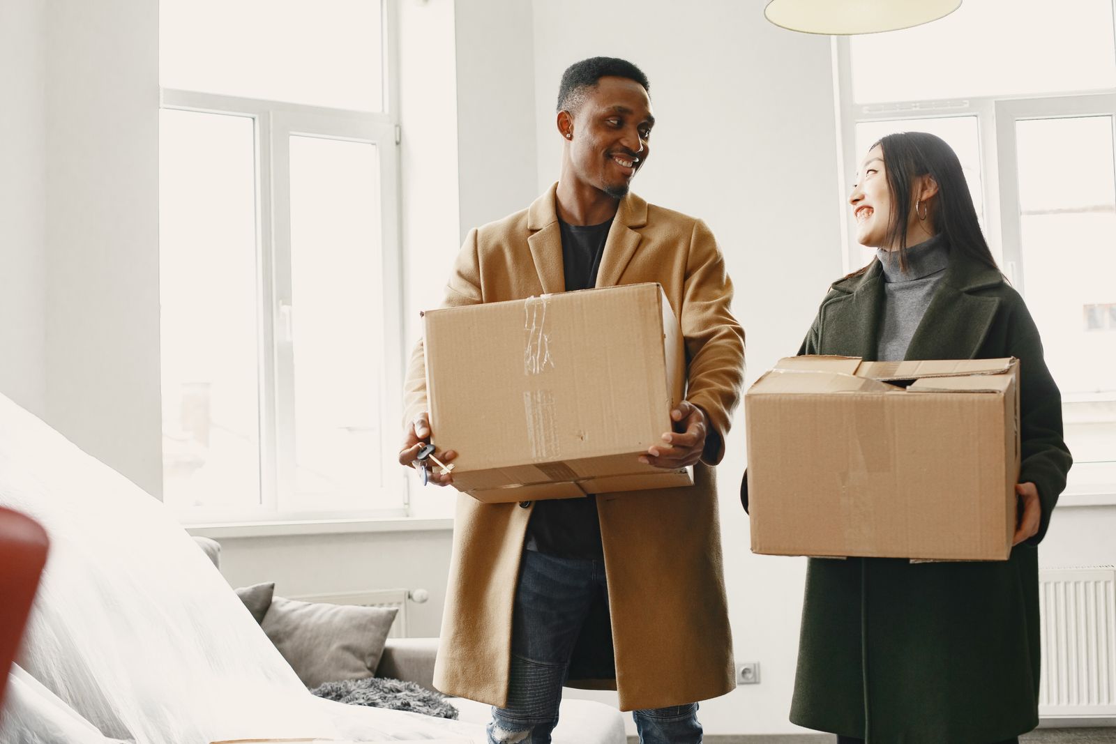 Couple carrying moving boxes while considering a relocation together