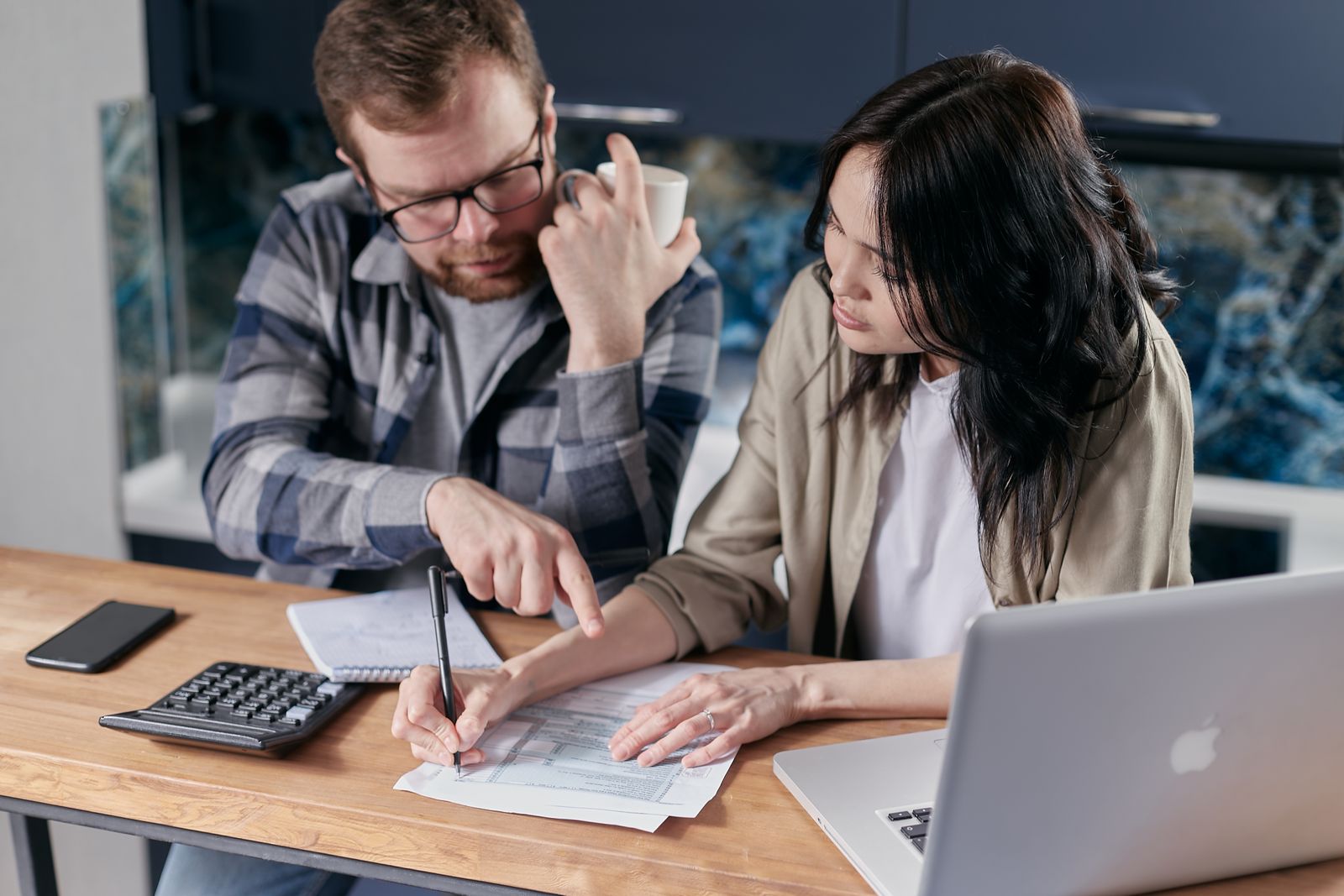 Couple planning shared bills with a calculator and laptop