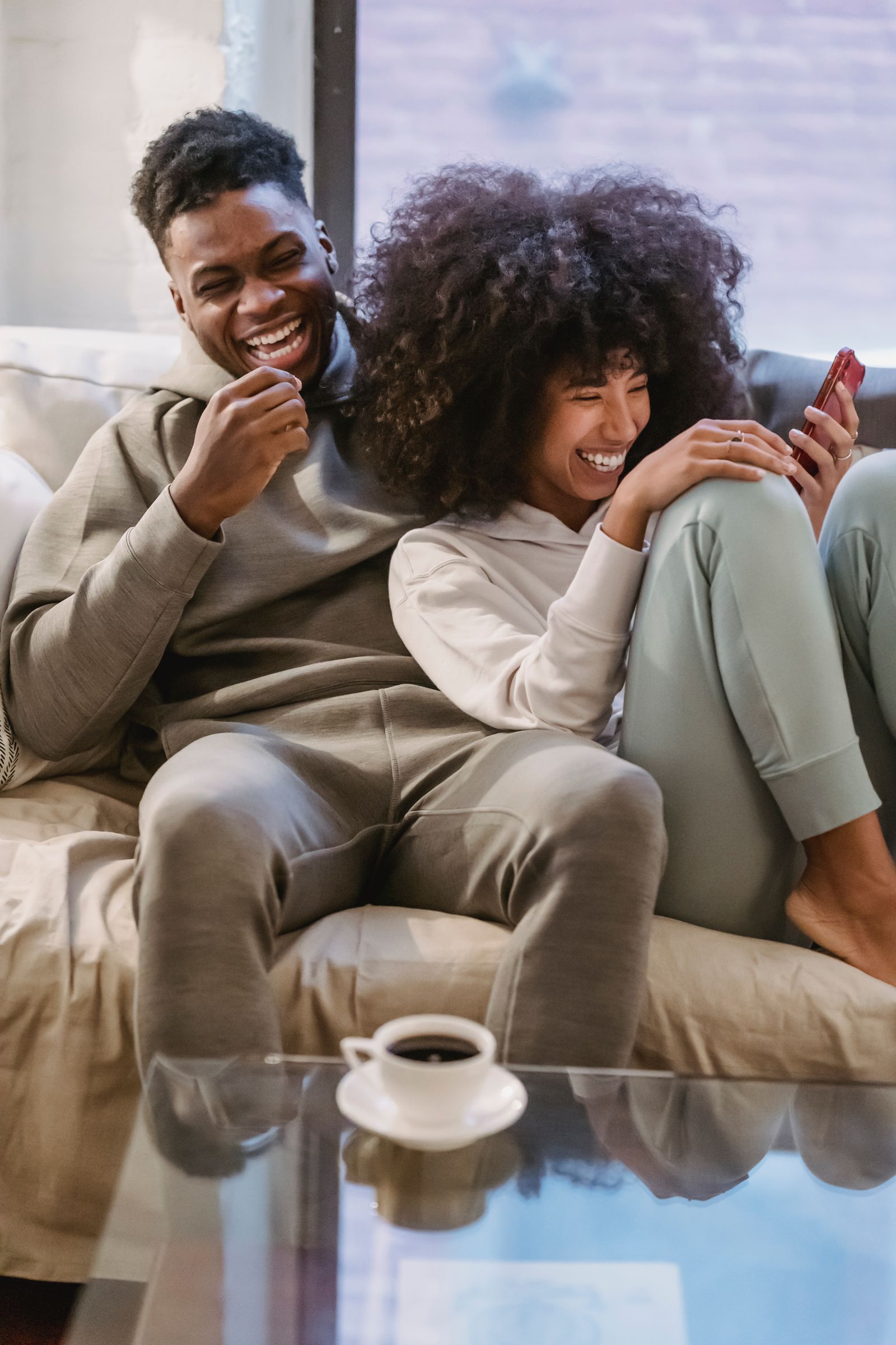 Couple laughing together while sharing something on a smartphone