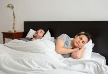 When Snoring Disrupts Your Relationship: How Couples Can Protect Sleep Without Blame One partner lying awake in bed while the other sleeps and snores