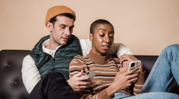 Couple sitting together on a sofa while each uses a smartphone