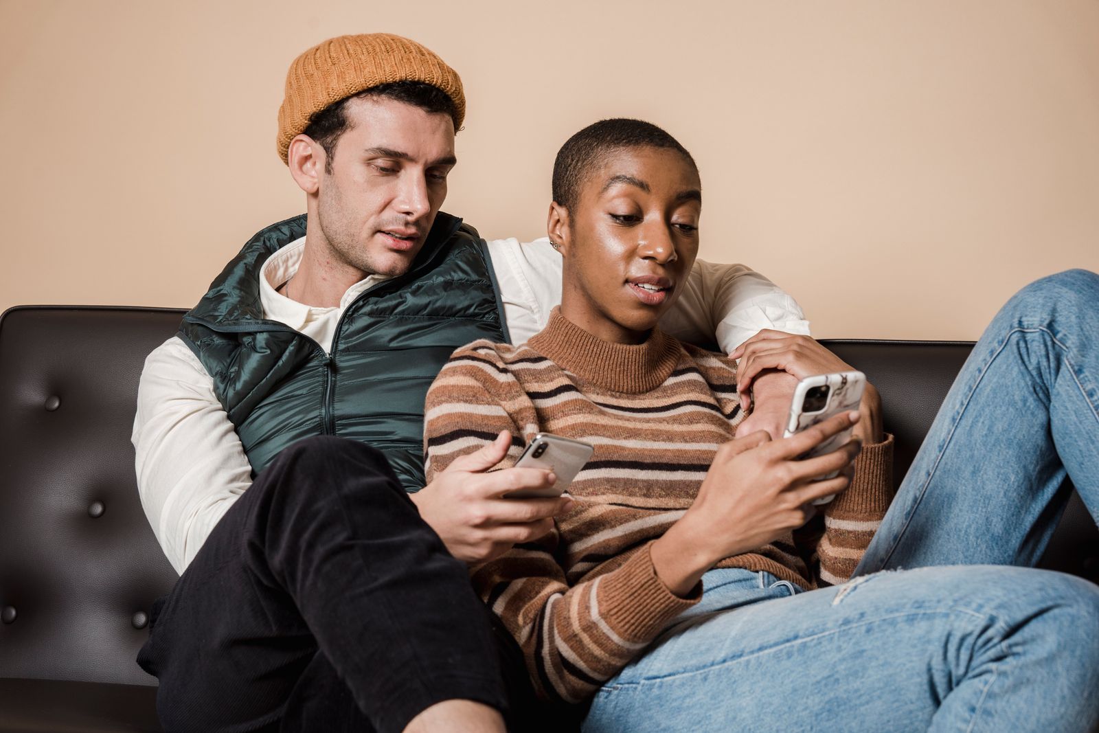 Couple sitting together on a sofa while each uses a smartphone