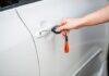 Hand using a key to secure a white car door before walking away