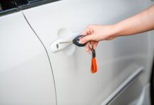 Hand using a key to secure a white car door before walking away