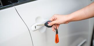 Hand using a key to secure a white car door before walking away