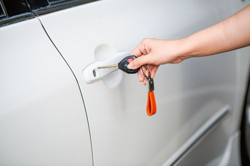 When Your Partner Leaves the Car Unlocked: How to Agree on a Security Check Hand using a key to secure a white car door before walking away