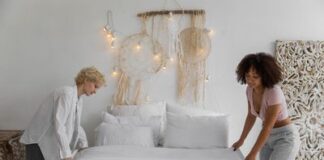 Couple changing bed sheets together in a shared bedroom