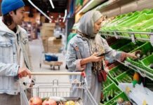 Couple checking a shared grocery list while shopping in a supermarket