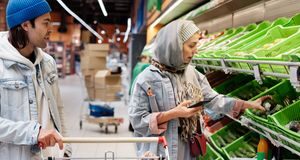 Couple checking a shared grocery list while shopping in a supermarket
