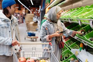 When Your Partner Buys Groceries You Already Have: How to Share the Shopping List Couple checking a shared grocery list while shopping in a supermarket