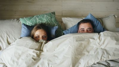 Couple resting comfortably in bed after discussing their bedding routine