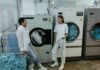 When Your Partner Never Cleans the Dryer Lint Trap: How to Share Laundry Safety Without Nagging Couple discussing laundry responsibilities beside washing machines