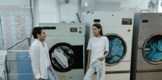 Couple discussing laundry responsibilities beside washing machines
