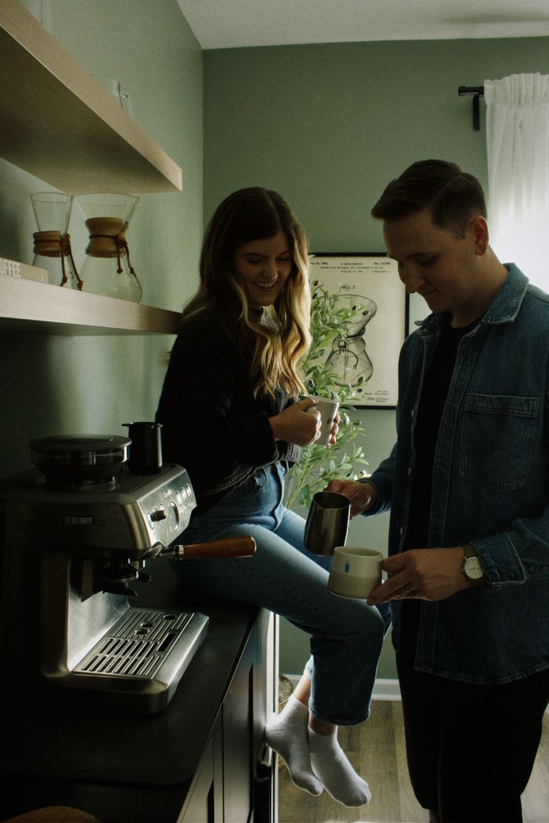 Couple preparing coffee together beside a coffee machine in their kitchen