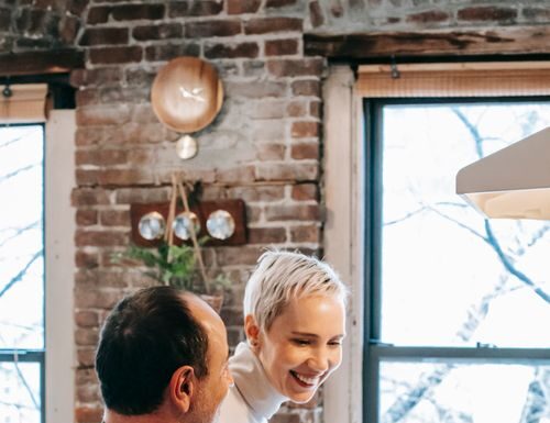 Couple cooking together beside a stovetop before sharing the kitchen cleanup