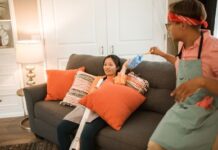 Couple sharing vacuum cleaner chores in their living room