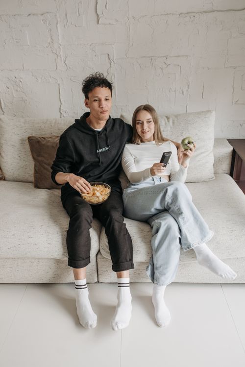 Couple relaxing on a sofa while watching television with a remote control