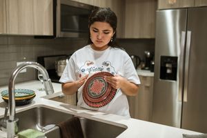 Person drying a clean bowl before putting dishes away in the kitchen