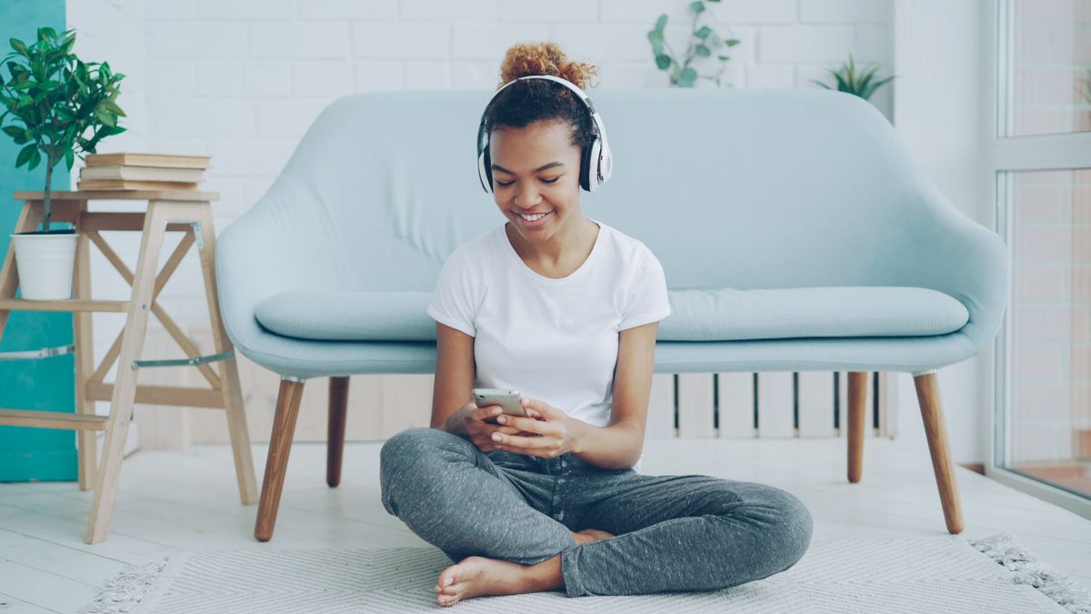 Woman using headphones with a smartphone while relaxing in a living room