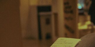 Person holding a pen and writing on paper indoors