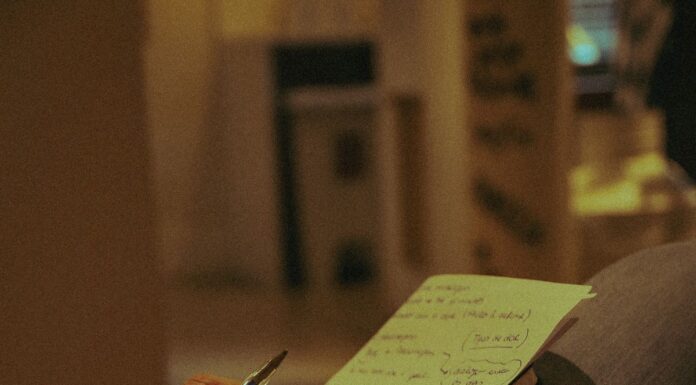 Person holding a pen and writing on paper indoors