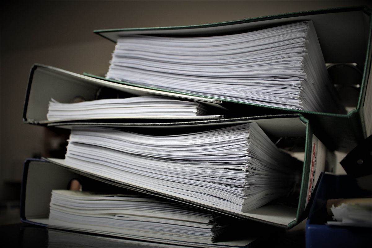 Stacked office binders filled with paper documents