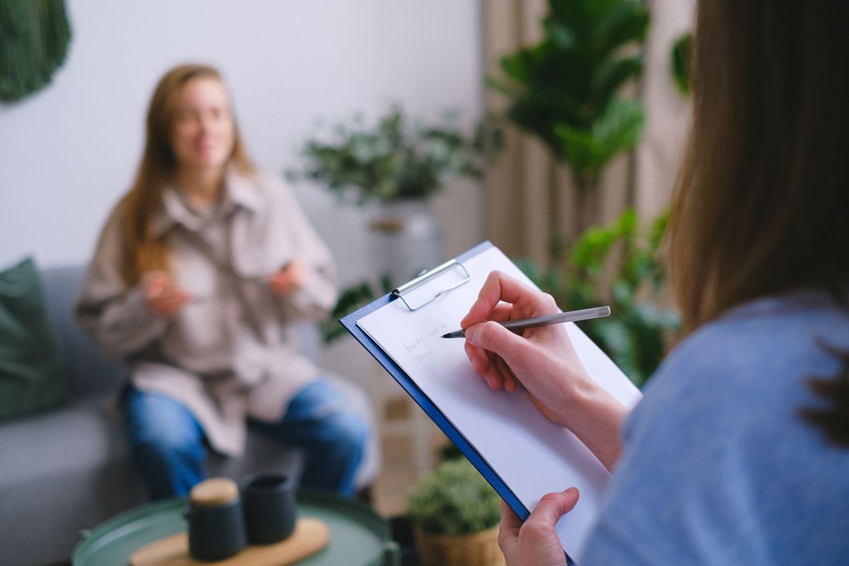 Close-up of a professional writing notes on a clipboard during a counseling session
