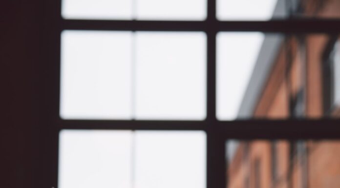 Laptop on a wooden desk beside large office windows