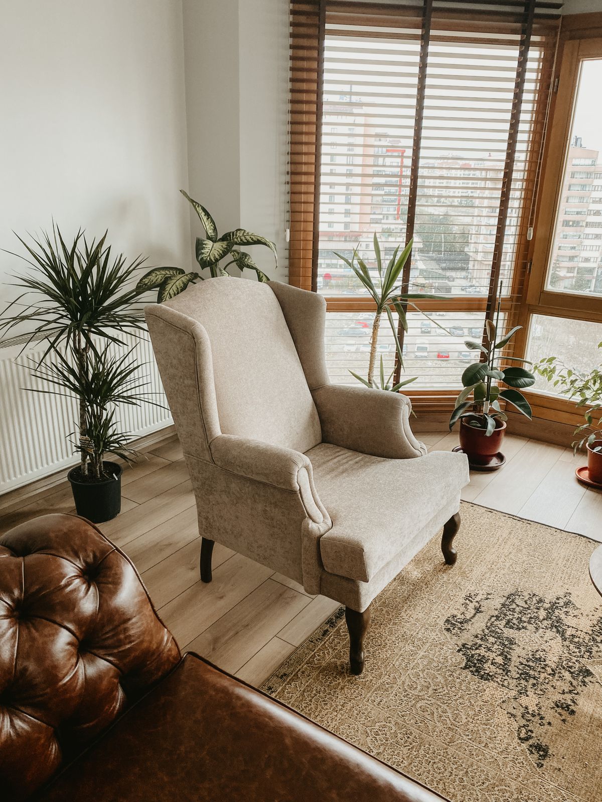 Beige armchair beside large windows and potted plants