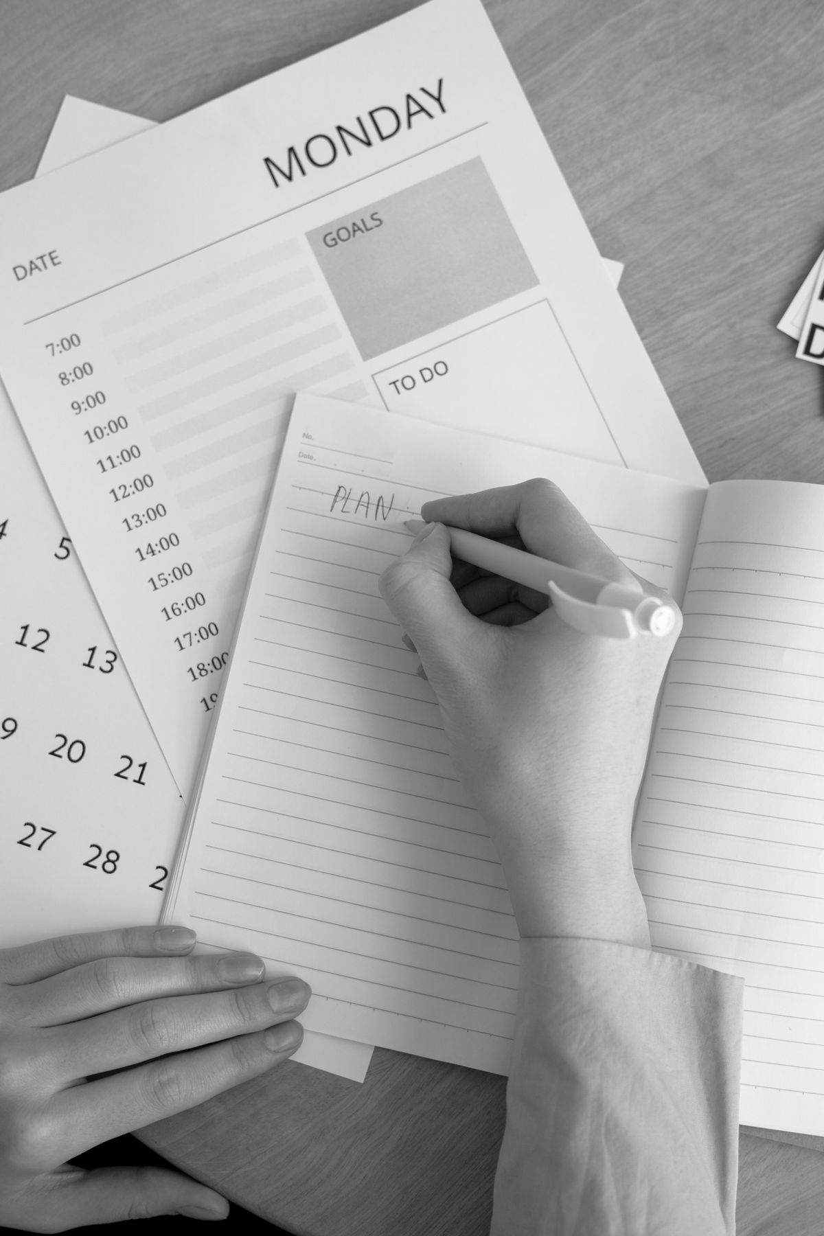 Hand writing notes beside a calendar in a black and white photograph